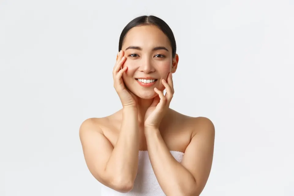 A smiling woman framing her jawline with her hands