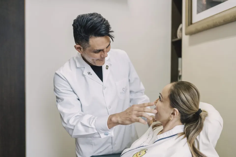 Dr Medora assessing a patient's under-eye area in the clinic